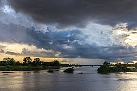 Blue and orange clouds over the Mekong with a pirogue running in the water at sunset in Don Det Laos.jpg